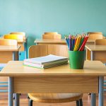 Empty classroom desk with books and pencils.